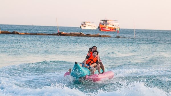 Alt: A group of tourists cherishing the thrilling banana boat ride on the open waters of Goa