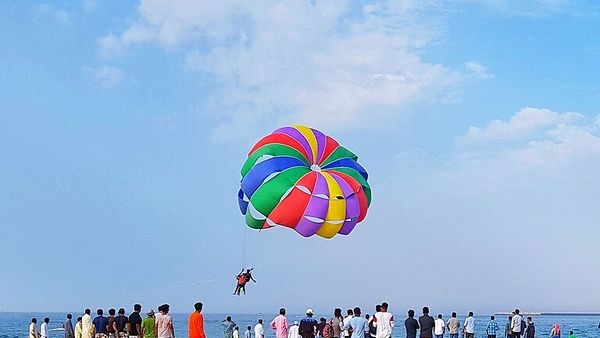Alt: A picture-perfect depiction of tourists enjoying parasailing on the sparkling waters of the Arabian Sea