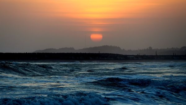 An exquisite panorama of a sunset at Kanyakumari beach radiating its golden hues on the serene blue water
