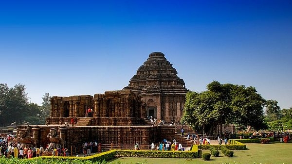 Image of a guide explaining the history and myths related to Konark Temple to a family Image of a guide explaining the history and myths related to Konark Temple to a family