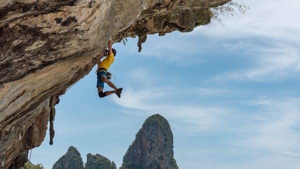 Rock climbers scaling the massive limestone cliffs in Krabi