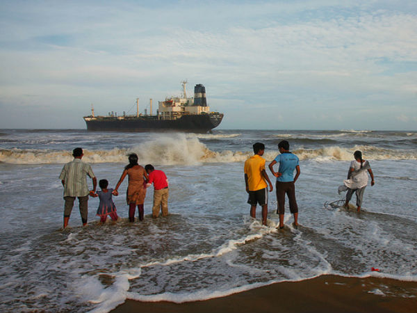 கப்பலைப் பார்த்தபடி அலைகளில் விளையாடும் இளைஞர் கூட்டம்